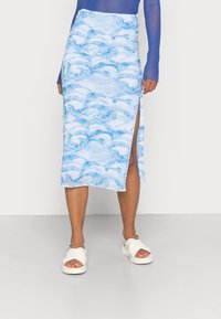 Sininen aalto-designin midi-hame, jossa on sivupistos, valmistettu kevyestä kankaasta. Yhdistettynä valkoisiin sandaaleihin, joissa on ristiraidat.