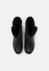 Botas de tobillo de cuero negro con un suave forro de piel sintética negra, cremallera lateral y punta redondeada. Suela plana sin patrones visibles.