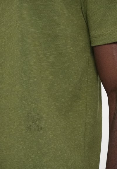 Πράσινο μπλουζάκι με κοντά μανίκια σε ύφασμα slub, με διακριτικό κεντημένο λογότυπο στο κάτω αριστερό μέρος.