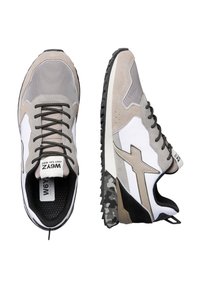 Un paio di sneakers grigie, bianche e nere con lacci neri, suola a motivo mimetico e linguetta con marchio visibile dalla vista superiore e laterale.