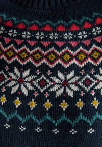 Marineblauer Strickpullover mit einem geometrischen Muster in Weiß, Rot, Pink, Gelb und Türkis, mit Schneeflocken- und Diamantmotiven im gesamten Design.