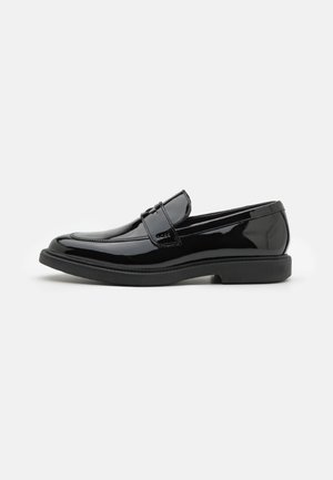 Mocassins en cuir verni noir avec un design élégant, bout arrondi et une simple bride sur le dessus. Semelle extérieure texturée pour une bonne adhérence.