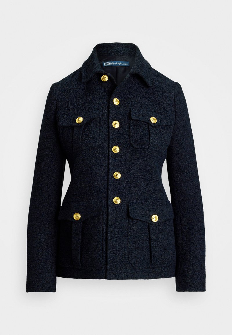 Tumši zili žaketi, kas izgatavots no teksturēta auduma, ar apkakles izgriezumu, zeltītām pogām un četrām priekšējām kabatām ar atloci.