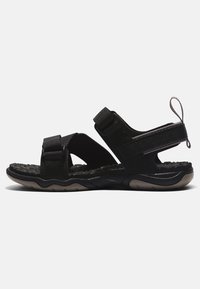 Svarta sandaler med justerbara remmar, texturerad sula, gummisula och en dragflik på hälen för enkel påtagning.