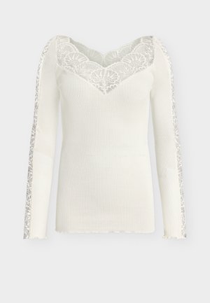 Άσπρο μακρυμάνικο τοπ με ριμπ ύφασμα, λουλουδάτο δαντελένιο V-λαιμόκοψη και δαντελένιες ρίγες που διατρέχουν και τα δύο μανίκια.