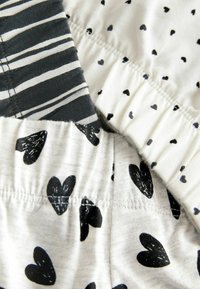 Black and white cotton fabric featuring two distinct patterns: one with horizontal stripes and the other with scattered black hearts.
