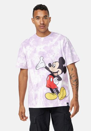 Camiseta de algodón con estampado de tie-dye en color liláceo, que presenta un gran gráfico de Mickey Mouse con pantalones cortos rojos y zapatos amarillos con detalles en negro.