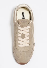 Beige anilīnnega tossud kreemjatest paelatest, lainete äärte ja tekstureeritud kanna detailidega. Omab logo muljet keeles ja kummist tallasid.