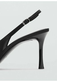 Zapato de tacón alto negro con acabado brillante, que cuenta con una delgada correa en el tobillo y un diseño de punta afilada. Parte superior texturizada y silueta elegante.