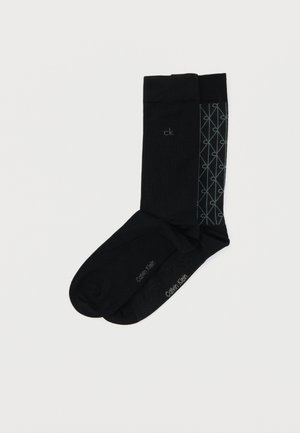 Șosete negre cu un design texturat ce prezintă un model geometric în gri, inscripționate "Calvin Klein" pe talpă. Material moale, lungime standard până la gleznă.