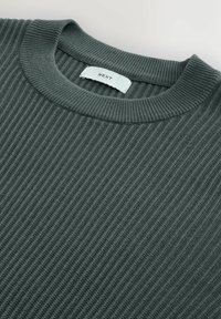 Maglione a coste di colore verde scuro con scollatura a girocollo. Presenta una leggera trama e un'etichetta con la scritta "NEXT" sul retro del colletto.