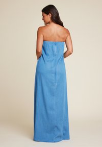 Ermeløs denim maxikjole i lyseblå, med elastisk topp, glidelås bak og rett snitt som flyter ned til gulvet.