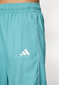 Turkise basketballshorts med elastisk livbånd, hvit piping langs siden og en hvit logo på venstre underben.