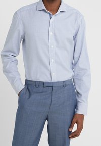 Camicia a righe blu chiaro con colletto, chiusura a bottoni frontale e maniche lunghe, abbinata a pantaloni blu chiaro.