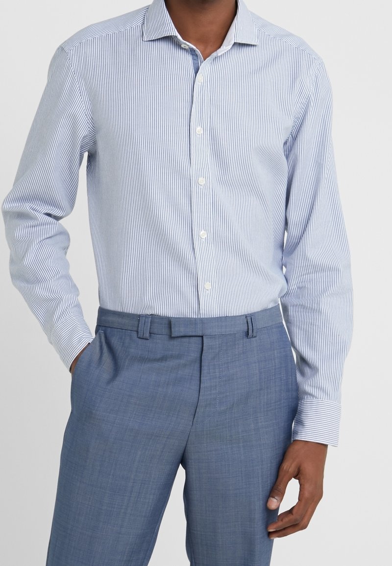 Camicia a righe blu chiaro con colletto, chiusura a bottoni frontale e maniche lunghe, abbinata a pantaloni blu chiaro.