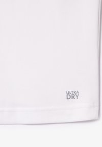 Vit träningsskjorta med en strukturerad tyg. Har "ULTRA DRY" i grått vid fållen. Enkel design, korta ärmar, inga ytterligare detaljer.