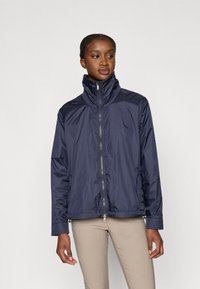 Granatowa nylonowa kurtka z wysokim kołnierzem, przednim zamkiem błyskawicznym i elastycznymi mankietami. Charakteryzuje się eleganckim wzornictwem oraz miękką, lekką teksturą.