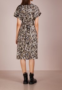 Leopardenmuster Kleid mit gebundenem Taillenbund, kurzen Ärmeln und einem mittellangen Saum. Hergestellt aus glattem Stoff und in den Farbtönen Braun, Grün und Weiß.