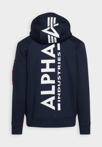 Hanorac cu glugă de culoare albastru marin, cu text alb mare "ALPHA INDUSTRIES" pe spate. Dispune de un buzunar lateral cu detalii roșii. Material moale.