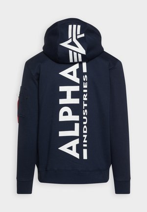 Námornícky modrá mikina s kapucňou s veľkým bielym textom "ALPHA INDUSTRIES" na chrbte. Obsahuje bočnú vrecko s červeným akcentom. Mäkká tkanina.