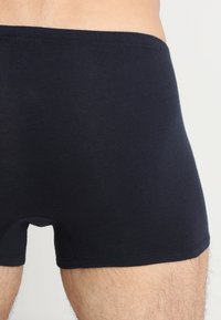 Boxer shorts neri in cotone con una vestibilità aderente, caratterizzati da una texture liscia e una vita elasticizzata. Nessun motivo o marchio visibile.