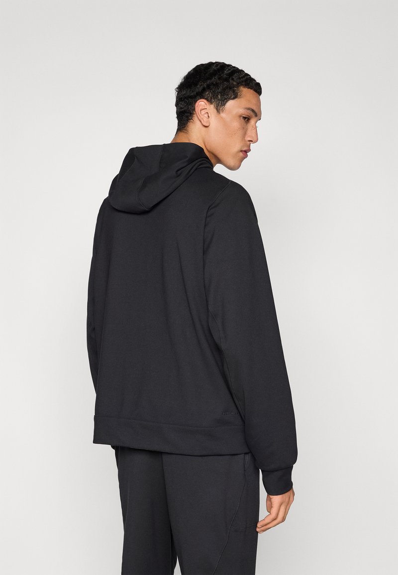 Black hooded sweatshirt made of soft fabric, featuring a relaxed fit, ribbed cuffs, and a visible seam detail at the back.