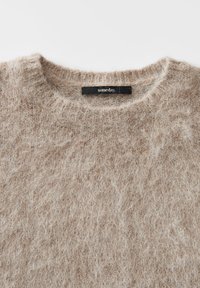 Soft beige fuzzy sweater with ribbed crew neckline and a black label reading "someday" sewn inside the collar.