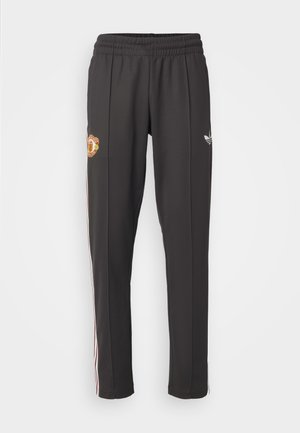 Svarta träningsbyxor med elastisk midja, med Manchester United-logotyp och vita ränder längs sidorna, tillverkade av mjuk väv.