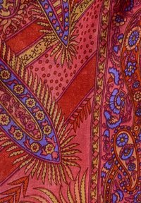 Tela roja con intrincados patrones florales y de paisley en azul y oro, con un detallado trabajo de línea y texturas variadas.