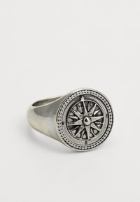 Anel de prata com um design de bússola, com uma face circular, direções cardeais gravadas e um acabamento brilhante.
