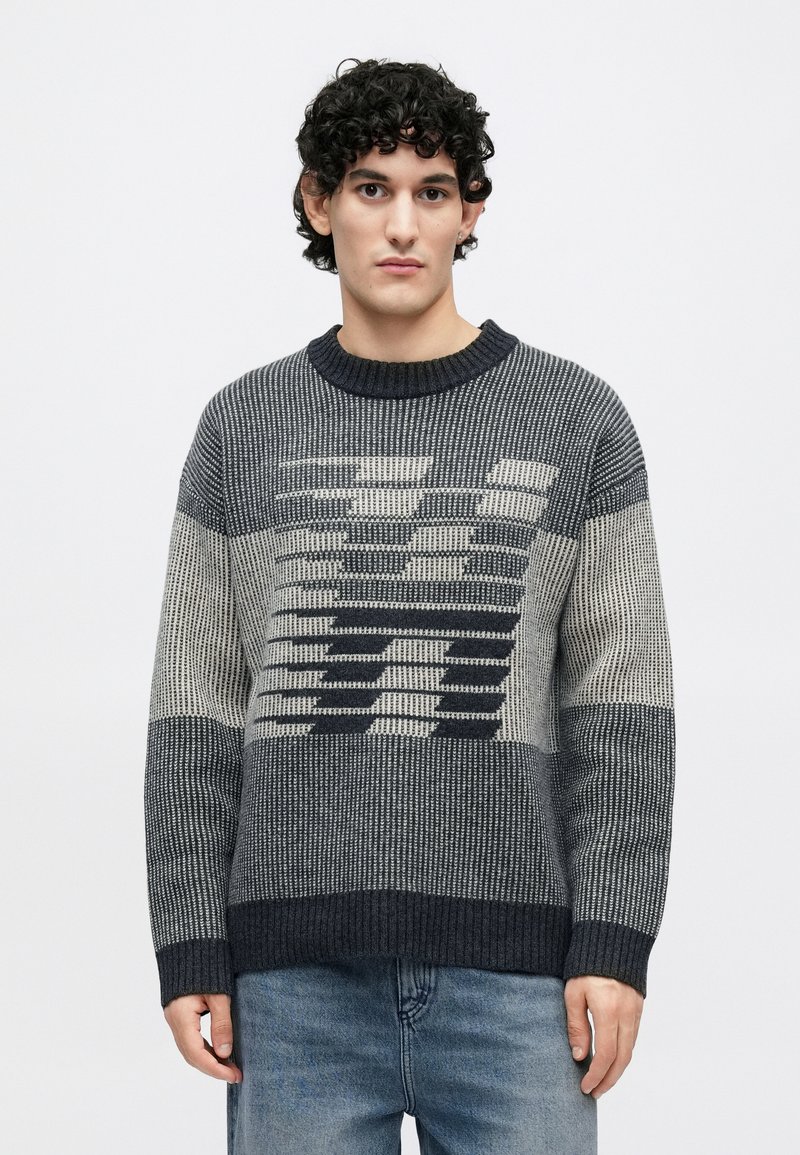 Pull texturé en nuances de marine et gris, avec un motif géométrique sur le devant. Col et poignets côtelés. Coupe classique.