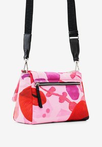 Borsa in tessuto rosa con finitura lucida, caratterizzata da una stampa floreale rossa e viola, chiusura con zip silver e una tracolla nera removibile.