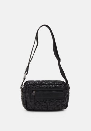Sac bandoulière noir avec motif embossé, poche avant zippée et bandoulière réglable sur un fond clair uni.
