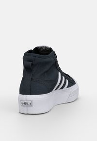 Sneakers alte in tela blu scuro con dettagli bianchi, caratterizzate da una suola robusta, tessuto strutturato e una etichetta con marca sul tallone.