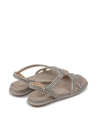 Platstellingen in licht taupe suede met zilveren rhinestone accenten en kruisbanden; textuur voetbed en metallic glitterdetails op de zool.