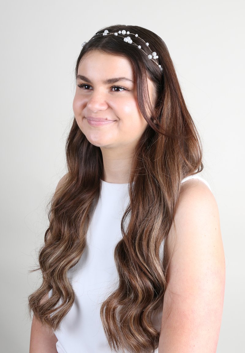 Accessorio per capelli a forma di corona con perline trasparenti e filo, caratterizzato da un disegno delicato, simile a fiori. Indossato da una persona con capelli lunghi e mossi.