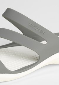 Sandales Crocs grises avec deux larges bandoulières, une semelle intérieure texturée blanche et une légère courbure à la semelle pour plus de confort et de soutien.