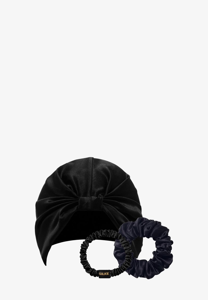 Turbante in velluto nero con grande nodo frontale, accompagnato da due fermagli per capelli in velluto, uno nero e uno blu navy scuro.