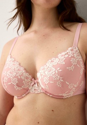 Pink lace bra with floral embroidery and scalloped edges, featuring adjustable straps and a small central bow detail. Textured fabric.