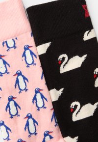 Două perechi de șosete: una roz cu modele de pinguini albaștri, cealaltă neagră cu lebede albe. Amestec de bumbac cu manșete cu model de jgheab.