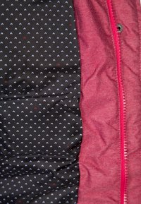 Tissu extérieur rouge à texture lisse, révélant une doublure noire ornée de petits cœurs bleus et rouges. Comprend une fermeture éclair et un bouton.