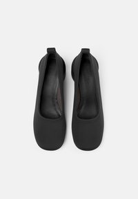 Svarta platta skor gjorda av mjukt material med rund tå och elastiska kanter för en tät passform, med en slät insida.