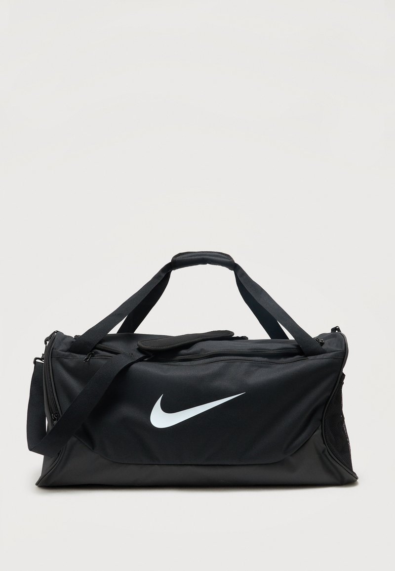 Μαύρη τσάντα Nike duffel με λευκό λογότυπο swoosh, διπλές λαβές, ρυθμιζόμενο ιμάντα ώμου και θήκες με φερμουάρ σε μονόχρωμο φόντο.