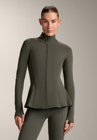 Athletic jacket in olive green, featuring a high collar, zip closure, fitted design, and side pockets. The material is smooth and stretchy.