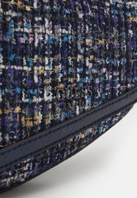 Pochette en tissu tissé bleu marine avec des fils multicolores violets et bleus, dotée d'un bord en cuir lisse et d'une plaque logo métallique.