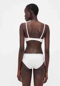 White bra and bikini set, featuring thin adjustable straps, elastic waistband, and smooth texture. Minimalist design without patterns.