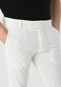 White trousers featuring a flat front, side pockets, and a button closure at the waistband, made from a smooth fabric with a lightweight texture.