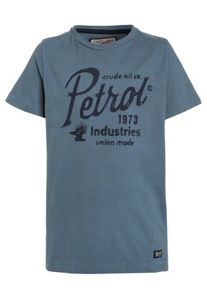 T-shirt bleu à manches courtes avec texte foncé "Petrol crude oil co. 1973 industries union made" et une petite étiquette noire près de l'ourlet.