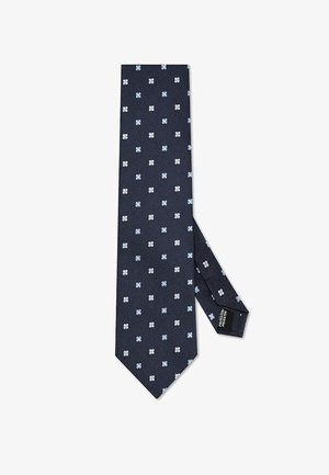 Granatowy krawat z drobnym, jasnoniebiesko-białym wzorem kwiatowym w kropki, złożony z tyłu, z widoczną metką "POLIESTER".
