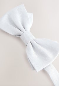 Light gray bow tie made of textured fabric. Features a central knot and wide, folded ends. Smooth surface with subtle pattern details.